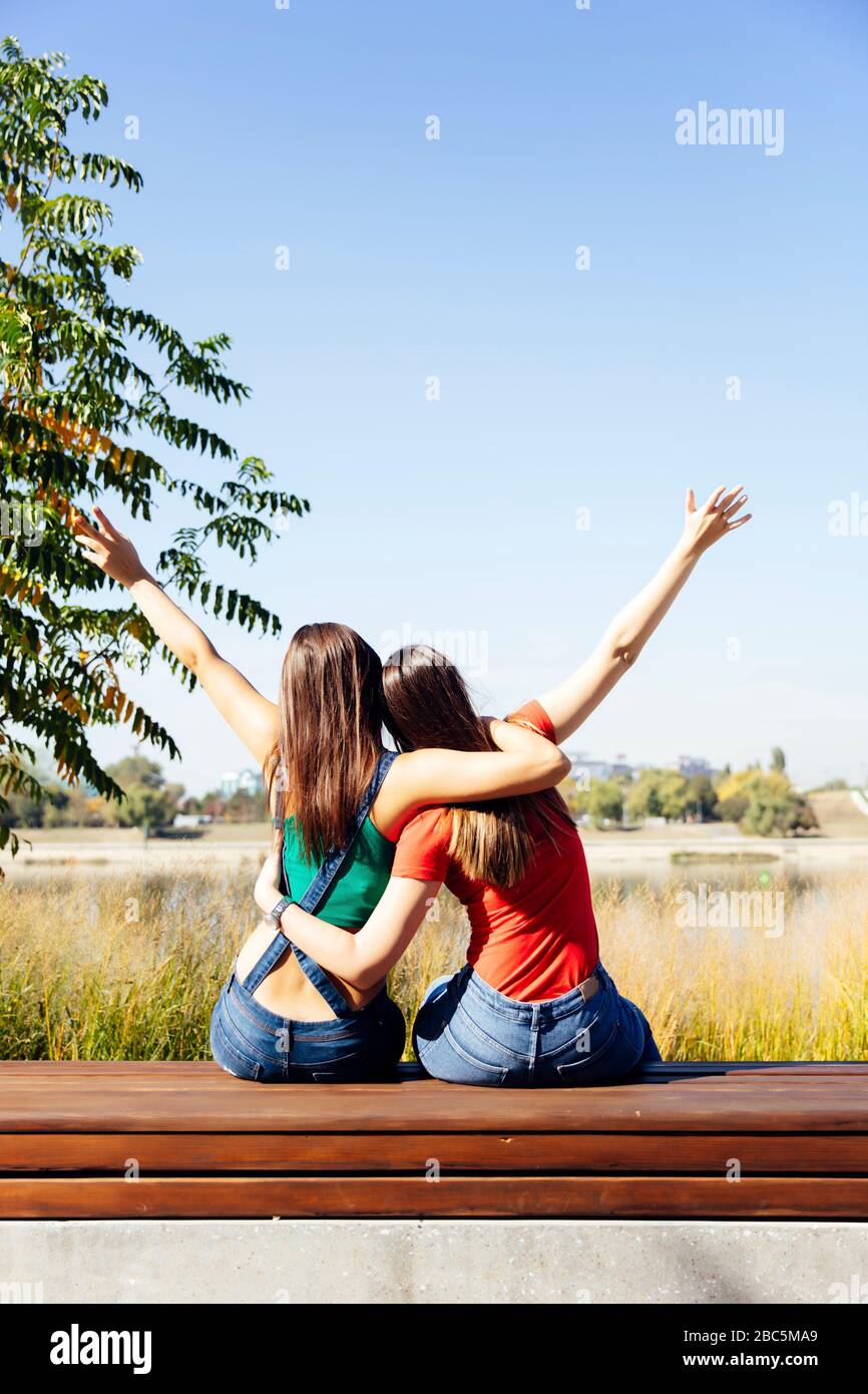Dos mejores amigas abrazándose juntas mientras se sientan al aire libre  Fotografía de stock - Alamy