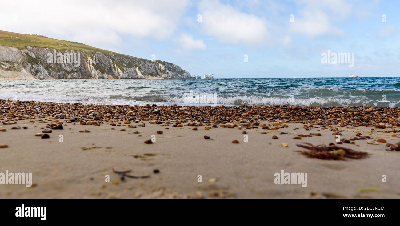 Vista de nivel bajo desde la playa de Alum Bay acroos arena y se mezclan con el faro de agujas Foto de stock