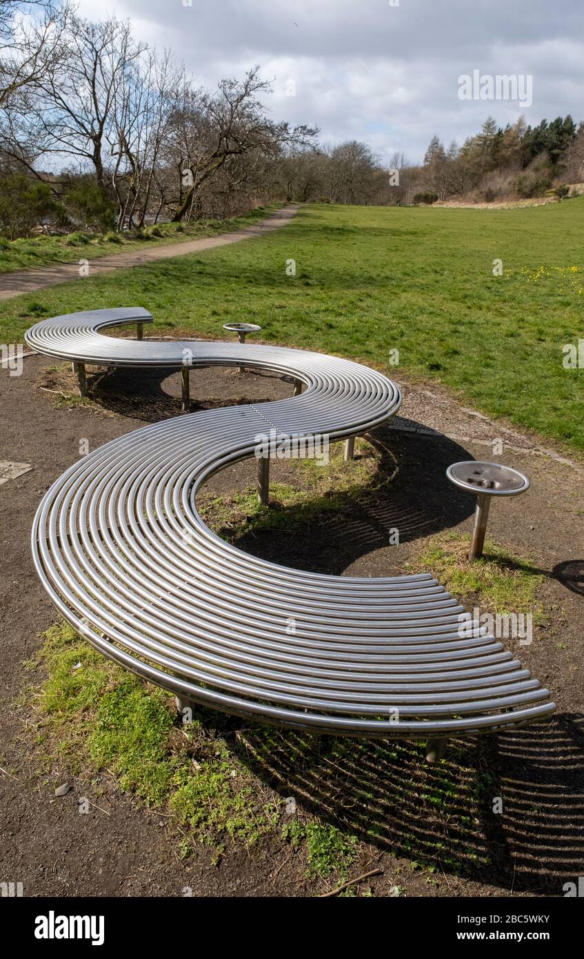 Asientos de diseño moderno en el parque de metal, en el camino junto al río del parque Almond, Livingston, West Lothian. Foto de stock