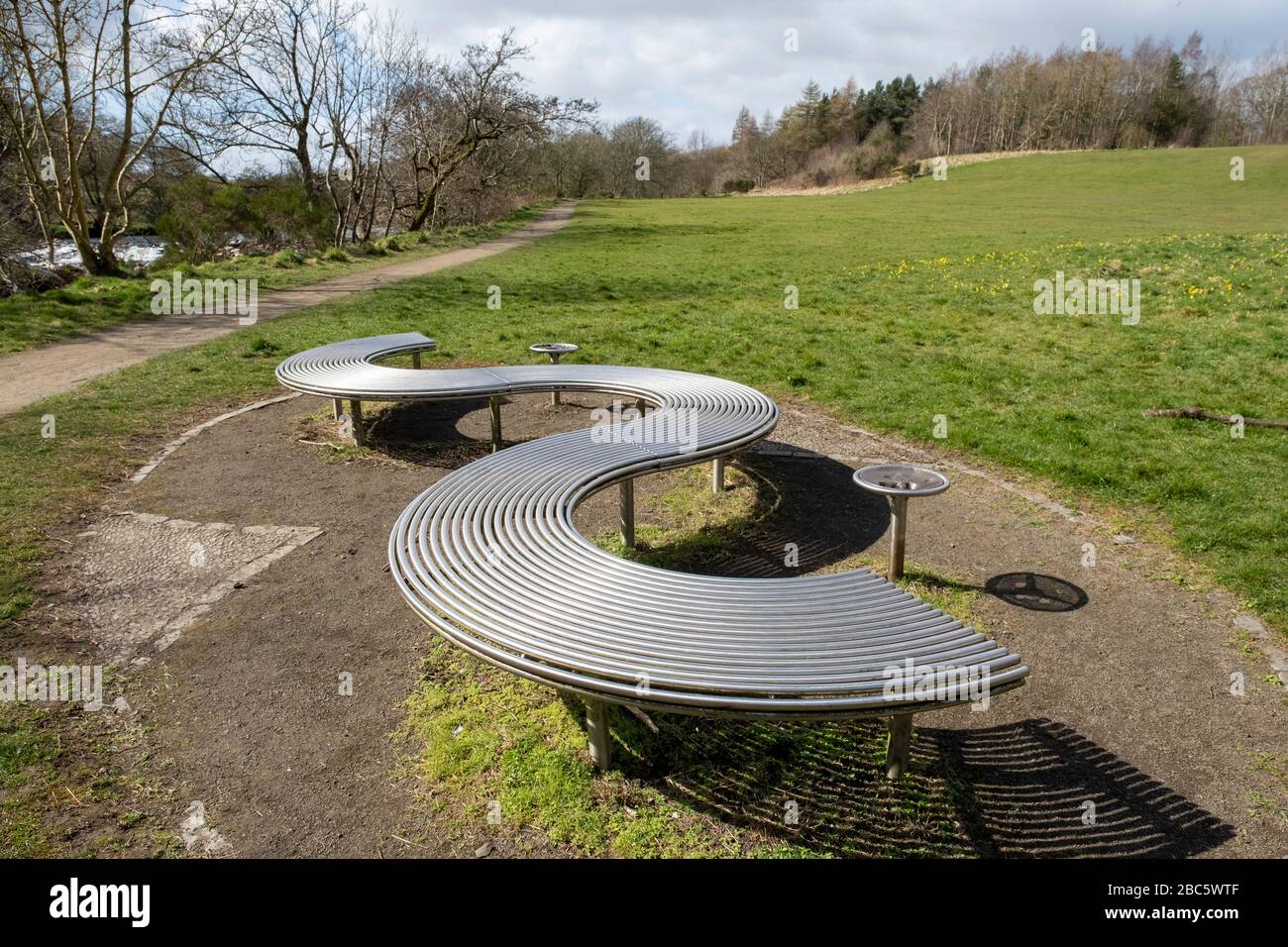 Asientos de diseño moderno en el parque de metal, en el camino junto al río del parque Almond, Livingston, West Lothian. Foto de stock