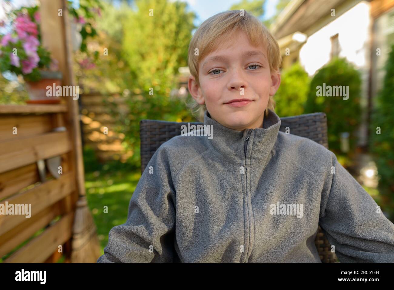Joven guapo niño sentado en el patio trasero Foto de stock