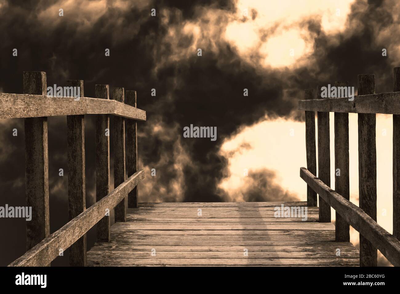 El final de un puente de madera que conduce hacia una gota. Las nubes oscuras y llenas de humo y la luz brillante dan una sensación de fuego del infierno y de apocalíptica ruina. Foto de stock