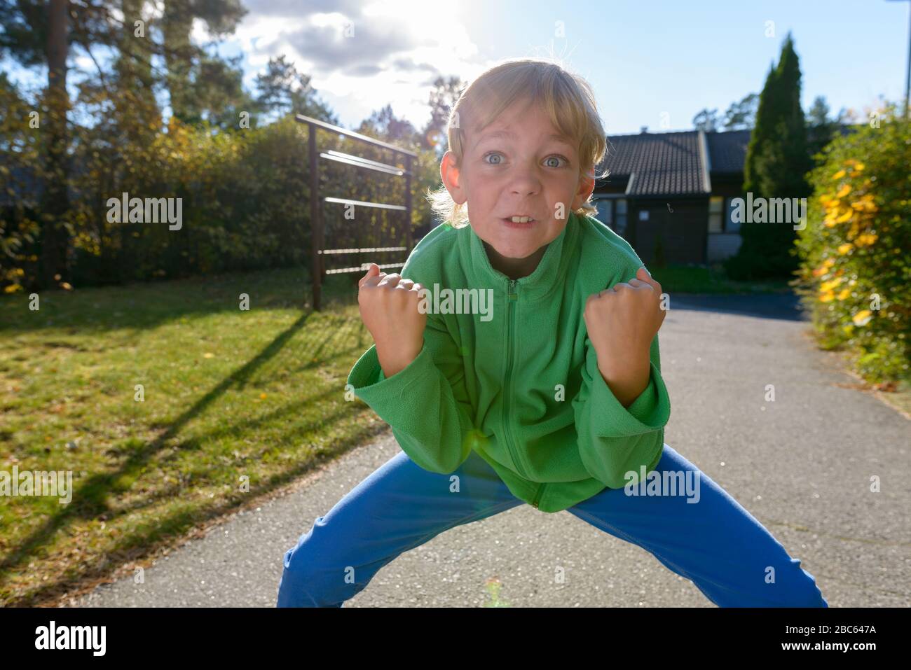 Niño estresado con puños levantados en el patio delantero Foto de stock