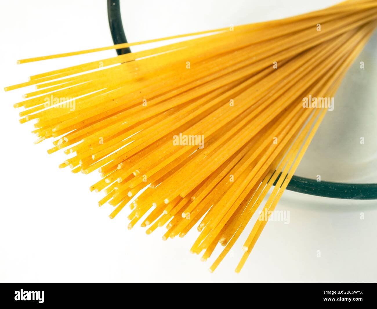 100 gramos de espaguetis de trigo integral en un recipiente de cristal sobre un mantel blanco Foto de stock