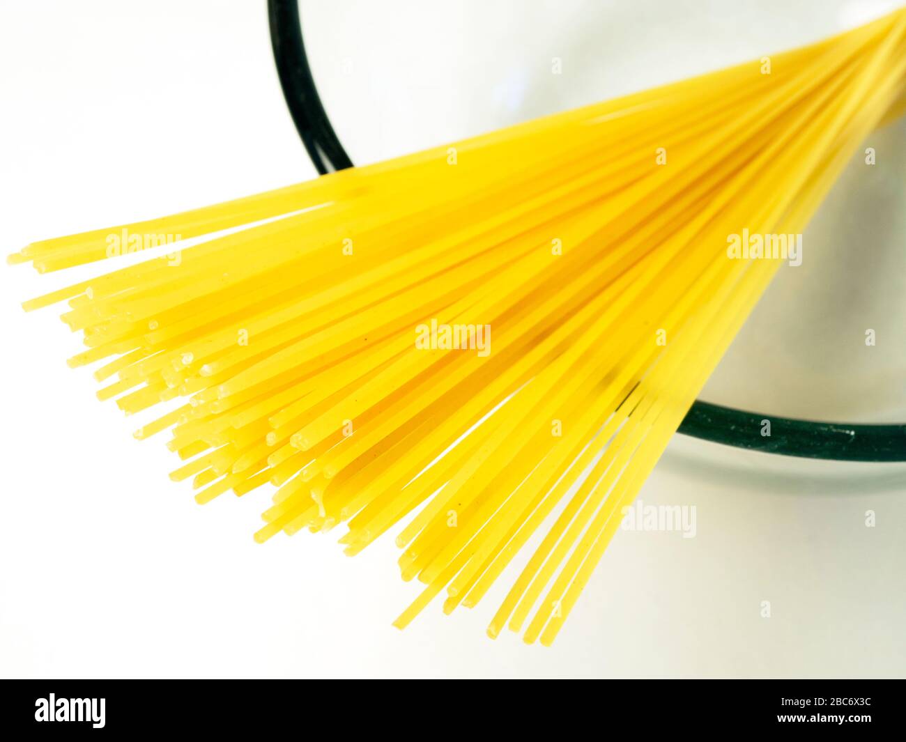 100 gramos de espaguetis en un tazón de vidrio sobre un mantel blanco Foto de stock