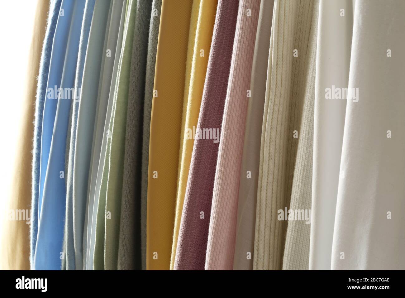 Mezcle en el estante telas, telas y paños de colores y diseños colgantes de rayas verticales. Mezcla de color pastel de tela. Foto de stock