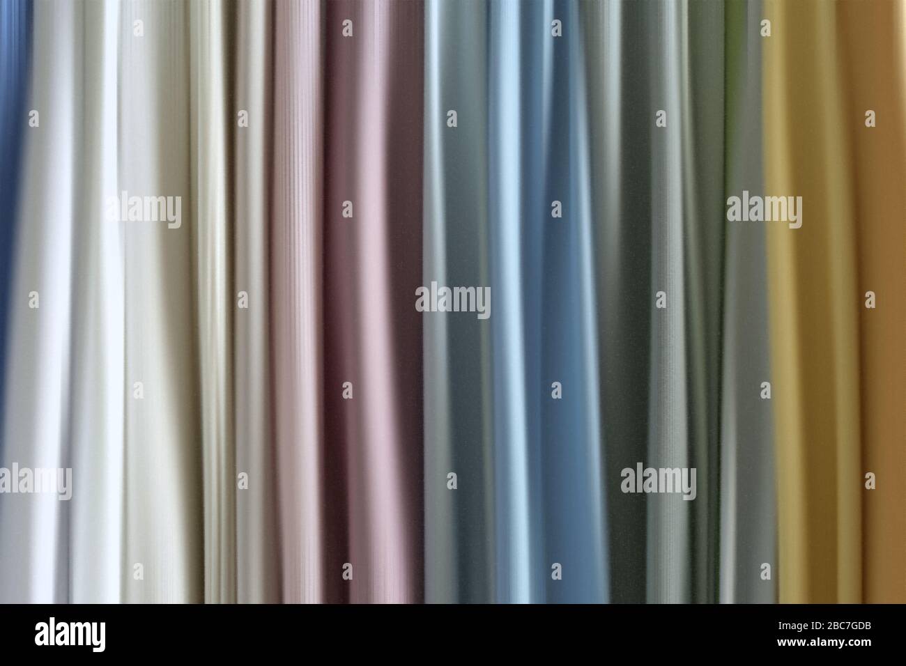Mezcle en el estante telas, telas y paños de colores y diseños colgantes de rayas verticales. Mezcla de color pastel de tela. Foto de stock
