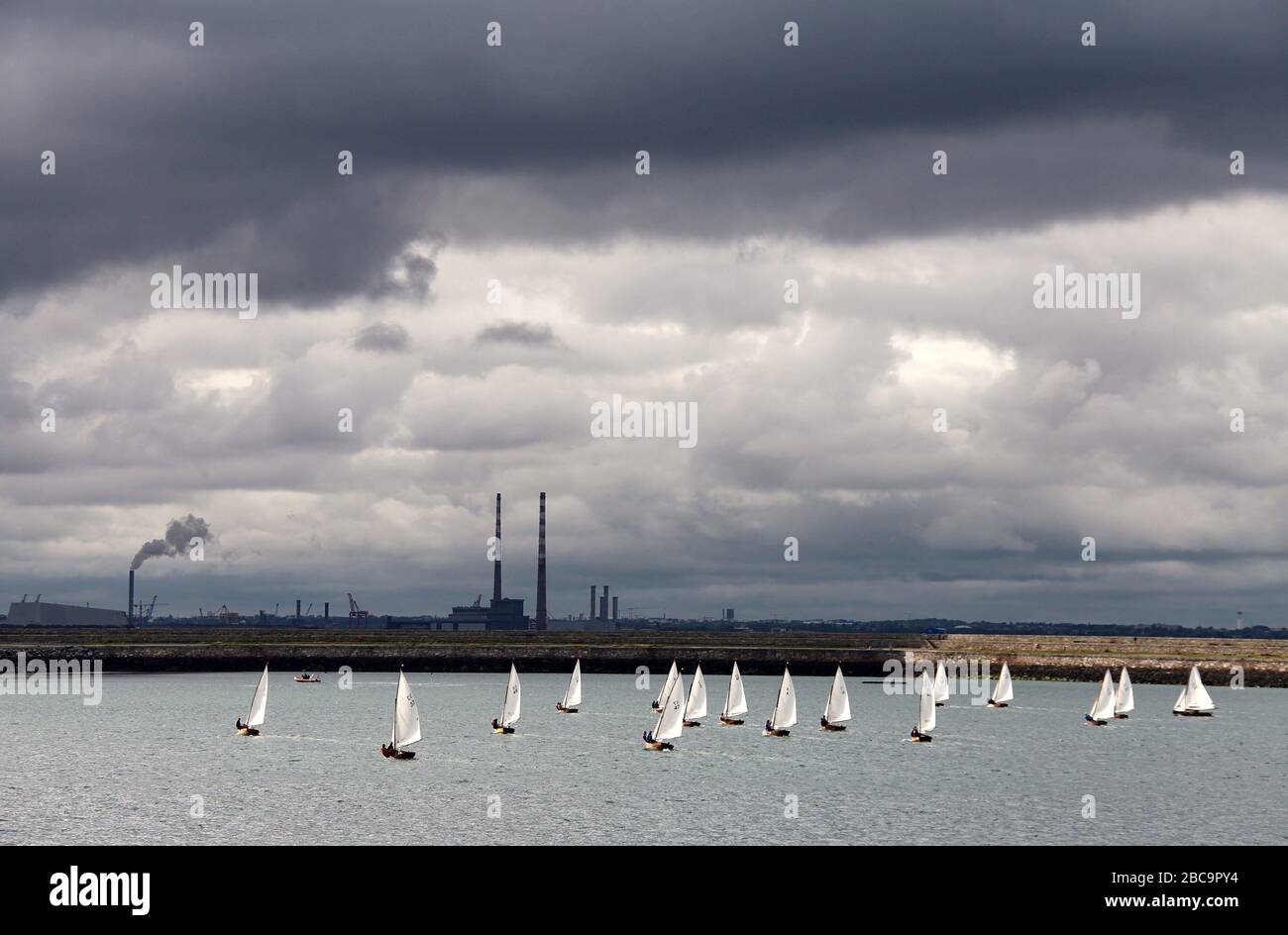 Barcos de vela en el puerto de Dun Laoghaire con Poolbeg Stacks en la distancia Foto de stock