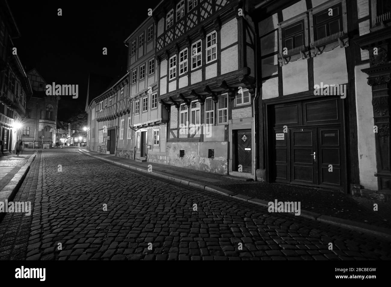 Imagen dramática en blanco y negro de un camino adoquinado entre casas de entramado de madera por la noche en Quedlinburg, Patrimonio de la Humanidad de la UNESCO Foto de stock