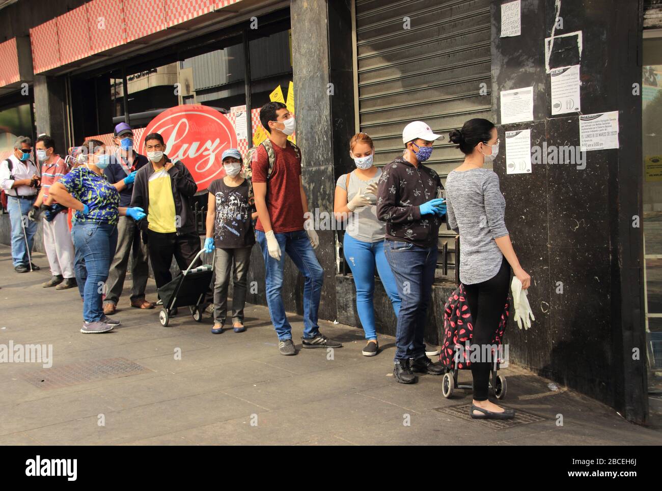 Caracas, Venezuela 31 de marzo de 2020: Personas que usan máscaras protectoras en línea esperando turnos para entrar en el supermercado durante una crisis de cuarentena Foto de stock