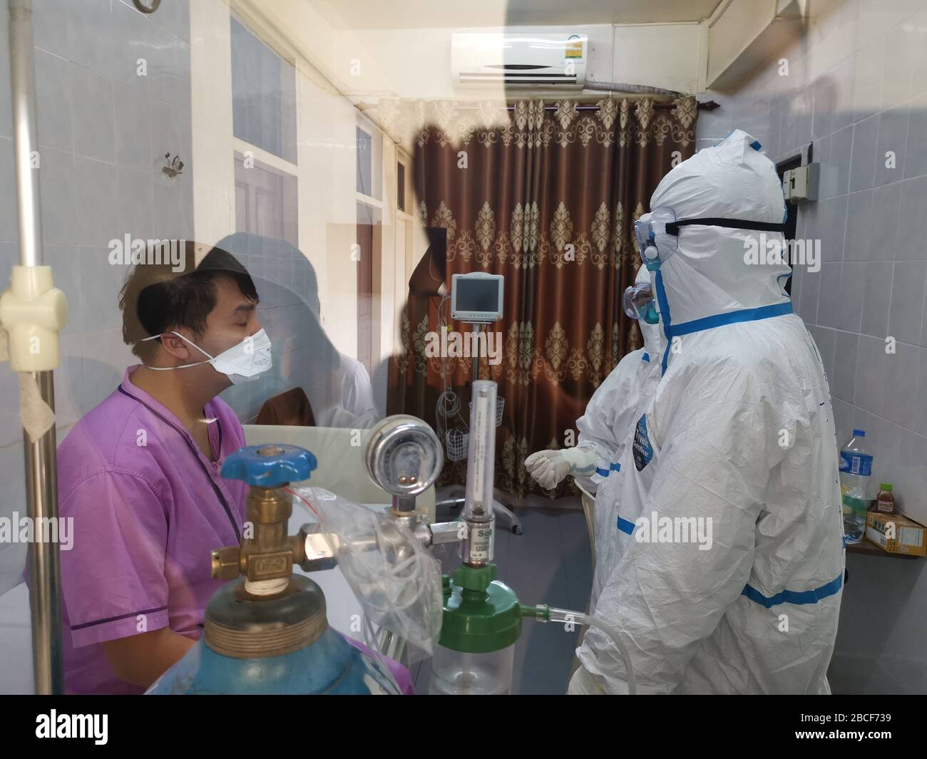 (200404) -- VIENTIANE, 4 de abril de 2020 (Xinhua) -- los miembros del equipo chino de expertos médicos antiepidémicos (R) se comunican con un paciente confirmado del COVID-19 en el hospital Mittaphab designado por el gobierno de Laos (Hospital 150) en Vientiane, Laos, 4 de abril de 2020. Poco después de llegar a Laos el 29 de marzo, el equipo de expertos médicos antiepidémicos de China comenzó a trabajar, investigando la situación epidémica y la condición médica local, y ayudando en la detección y el diagnóstico de COVID-19. Se unieron a la parte lao en un esfuerzo por trazar la hoja de ruta antiepidémica del país. (Exp. Médica antiepidémica China Foto de stock