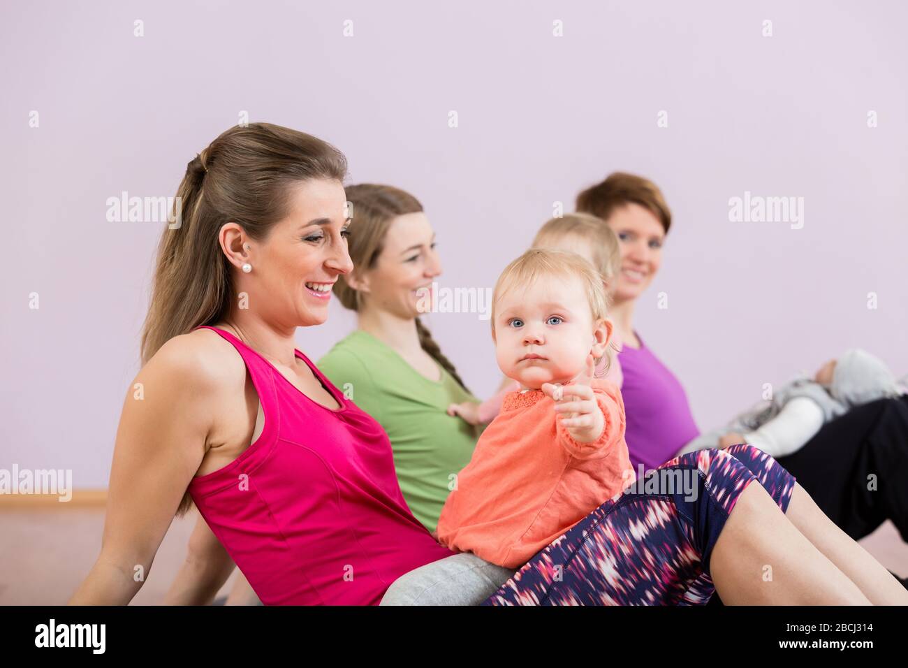 Las madres ejercitan con los bebés en el curso del ejercicio postnatal Foto de stock