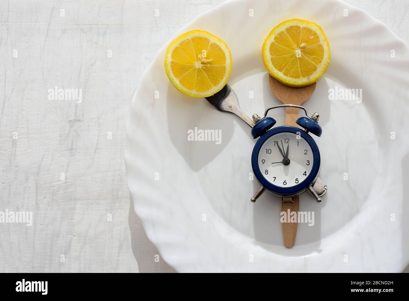 Limón fresco en plato blanco, cubiertos y reloj despertador servido para la  cena o almuerzo / Tiempo para perder peso / Comer control / dieta concepto  Fotografía de stock - Alamy