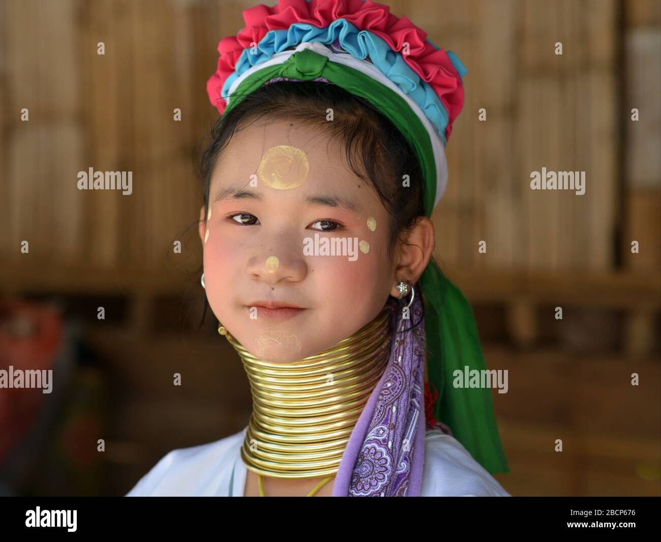 Bastante tailandés / birmano de cuello largo Kayan pre-adolescente (“mujer jirafa”) con anillos de latón cuello / bobinas y thanaka en su cara posan para la cámara. Foto de stock