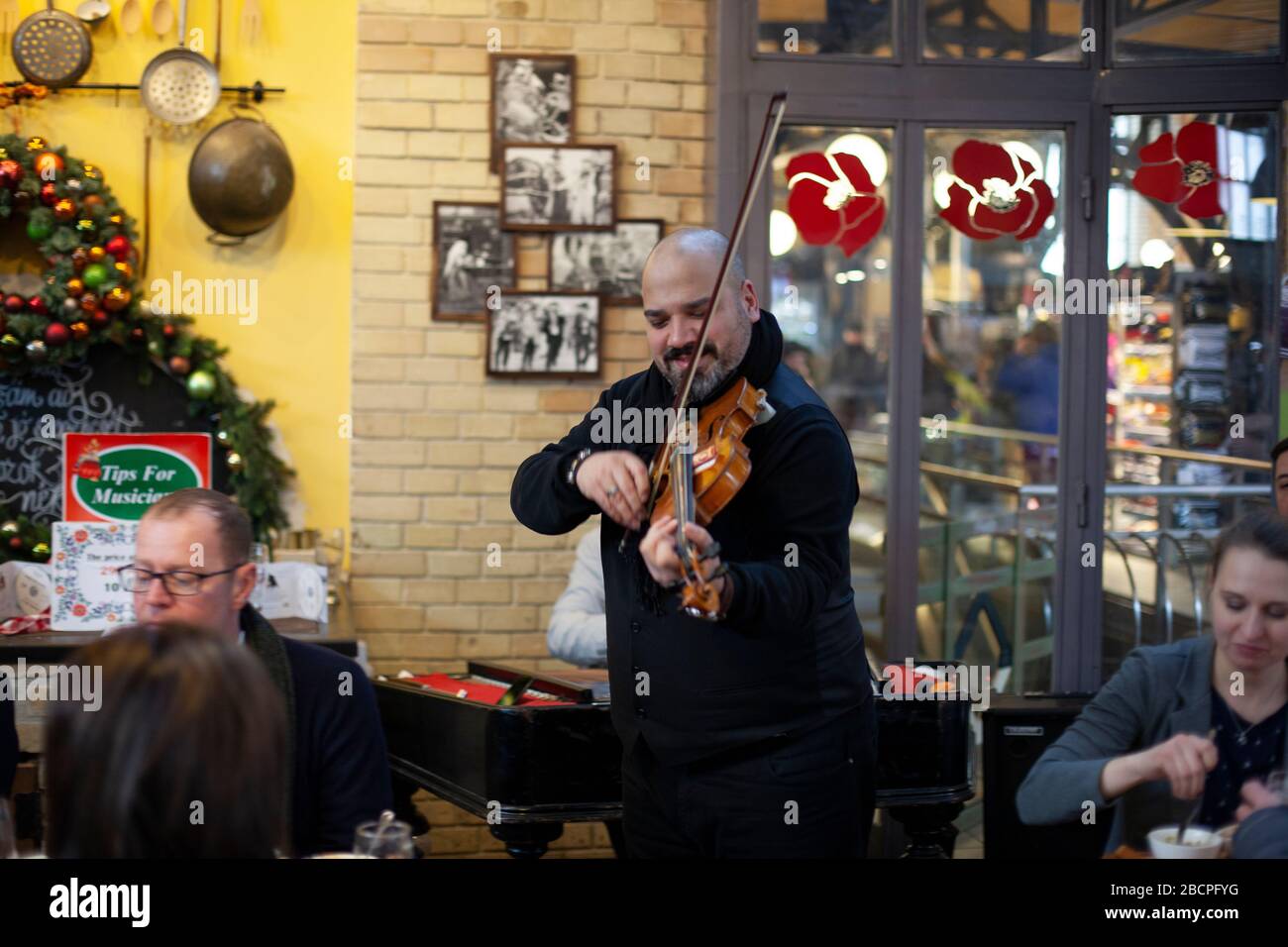Un fiddler juega a un público de restaurantes en el Central Market Hall, Budapest, Hungría en invierno Foto de stock