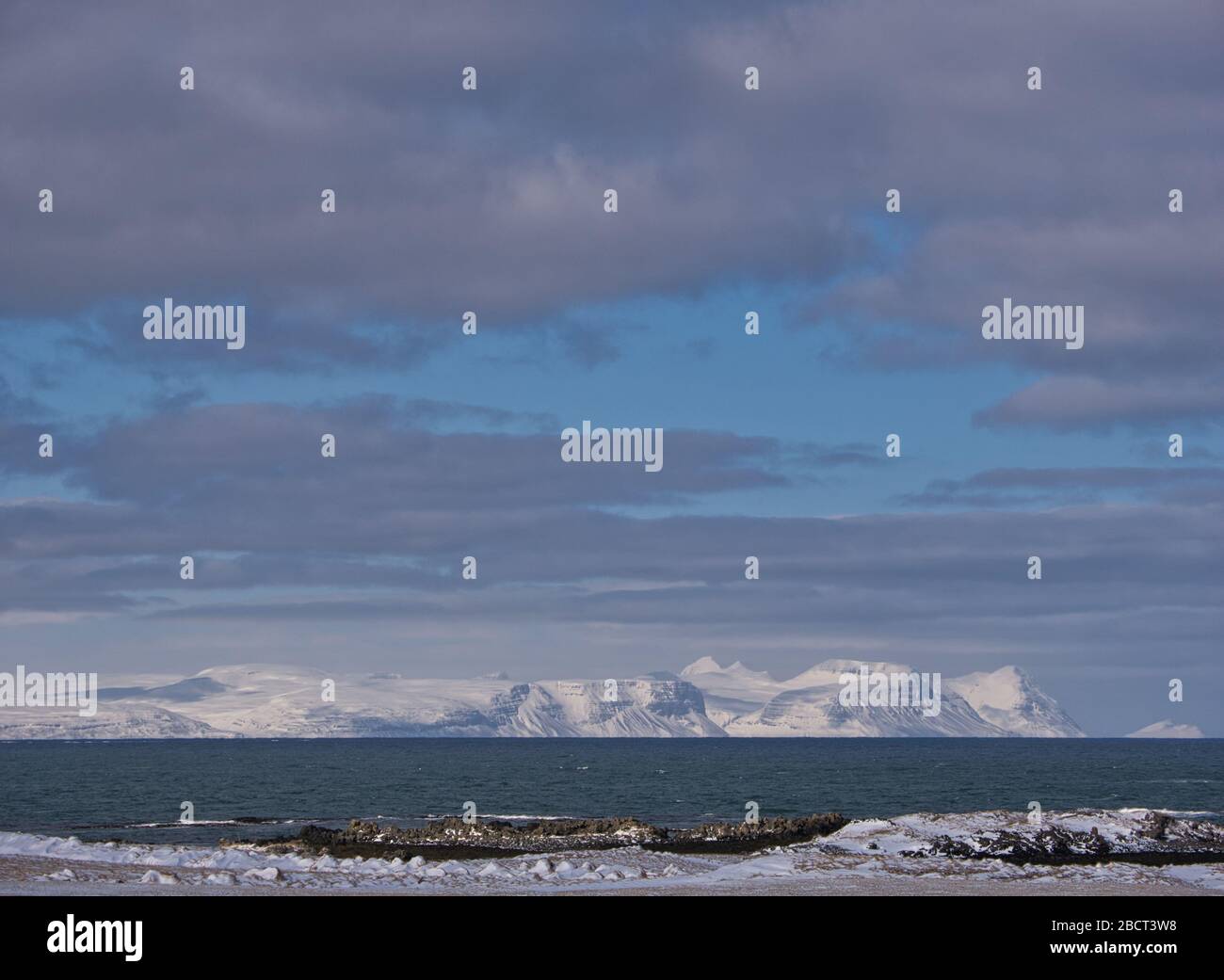 Nubes sobre las montañas cubiertas de nieve en la costa de Islandia Foto de stock