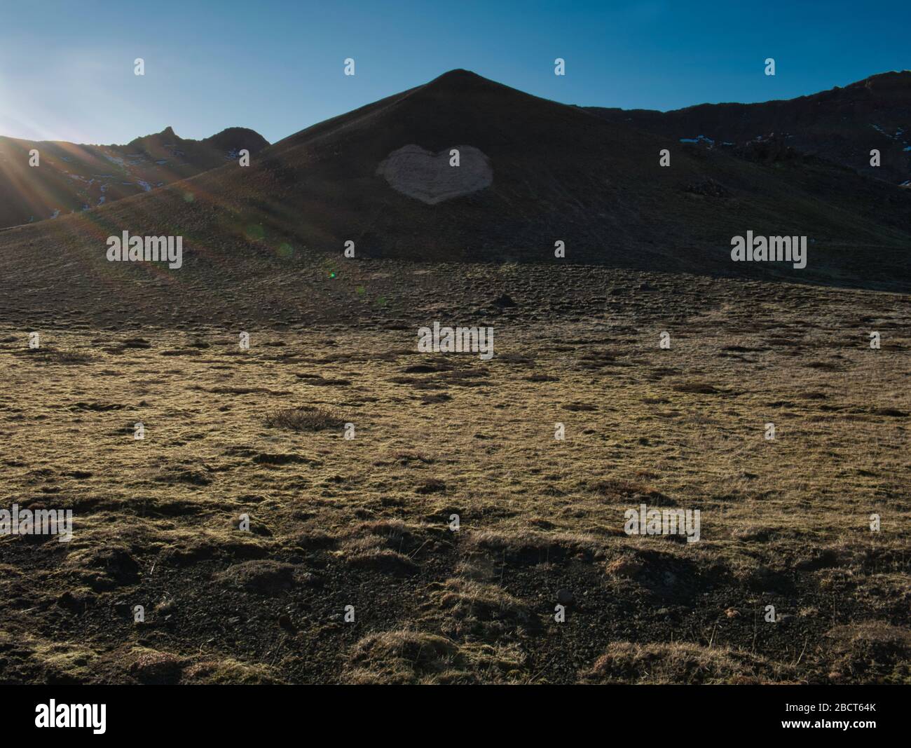 Un corazón grande en una ladera de una montaña en Islandia con rayos de sol Foto de stock