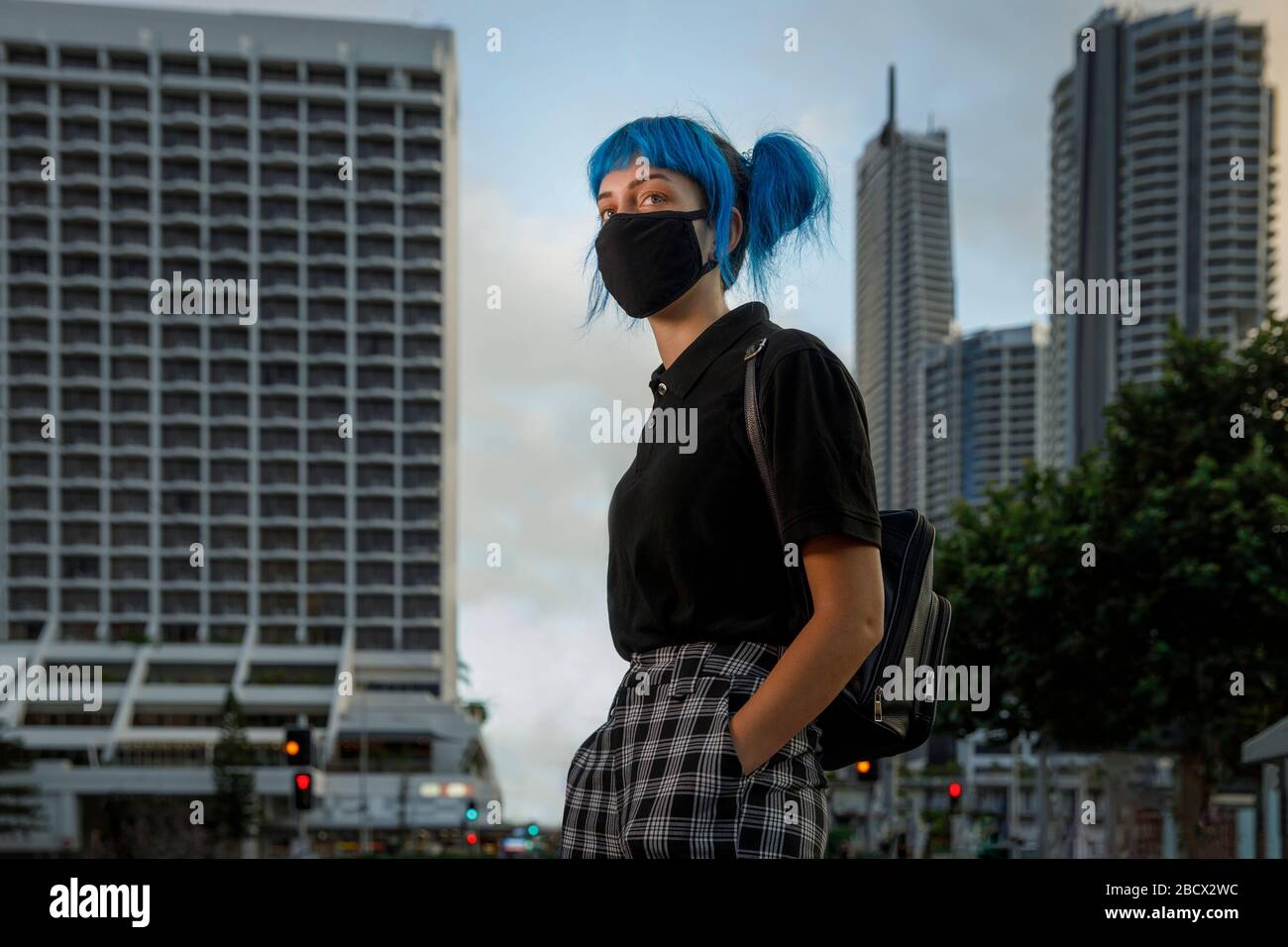 mujer joven con máscara médica en la calle moderna de la ciudad, chica de moda con el pelo azul con máscara médica protectora en medio de temores coronavirus Foto de stock