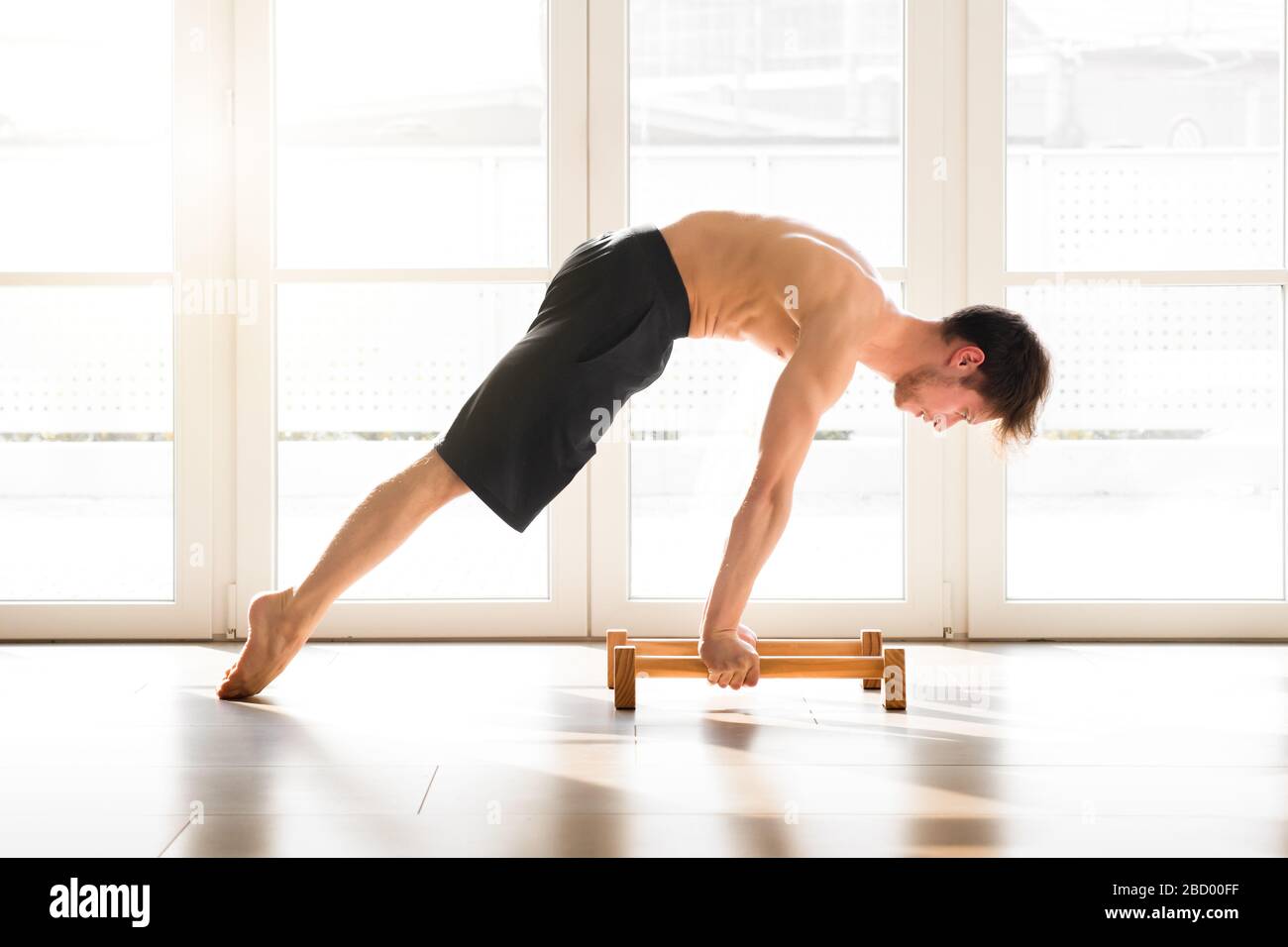 Ajuste hombre joven haciendo un planche calienthenics pose equilibrio en  los brazos rectos en barras del piso con el cuerpo levantado en un gimnasio  alto de la llave en una salud y