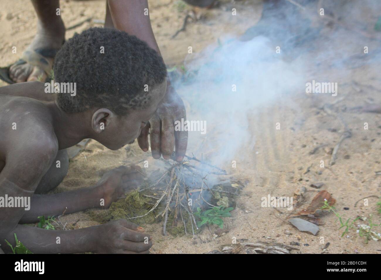 África, Tanzania, el lago Eyasi, el joven niño Hadza enciende un incendio. Hadza, o Hadzabe, es un grupo étnico indígena en el norte-centro de Tanzania, livin Foto de stock