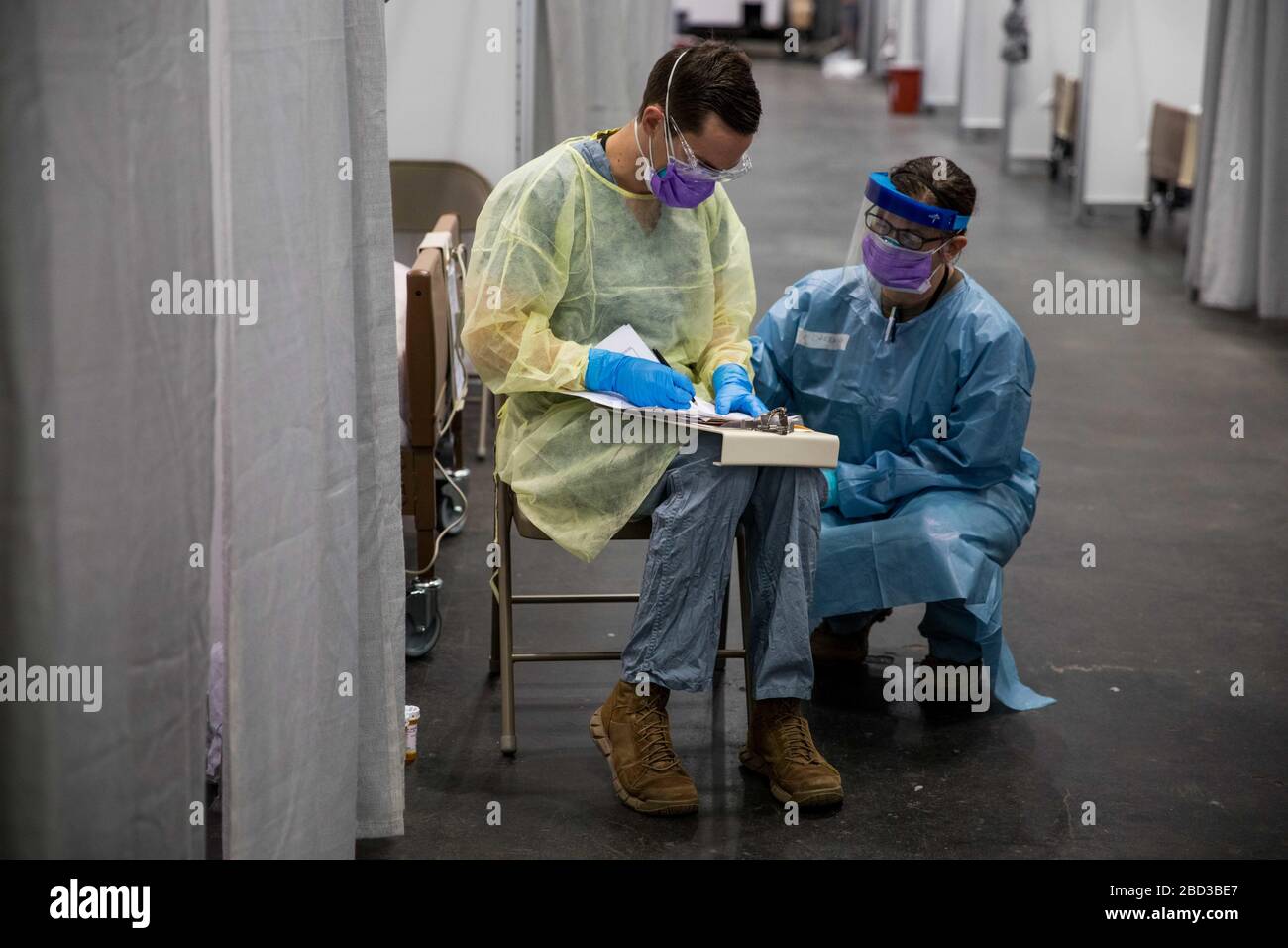 El personal médico del Ejército de los Estados Unidos completa el papeleo en la unidad de cuidados intensivos de la Estación médica Federal COVID-19, centro de ayuda para la pandemia de coronavirus establecido en el Centro Jacob Javits 5 de abril de 2020 en la ciudad de Nueva York, Nueva York. Foto de stock