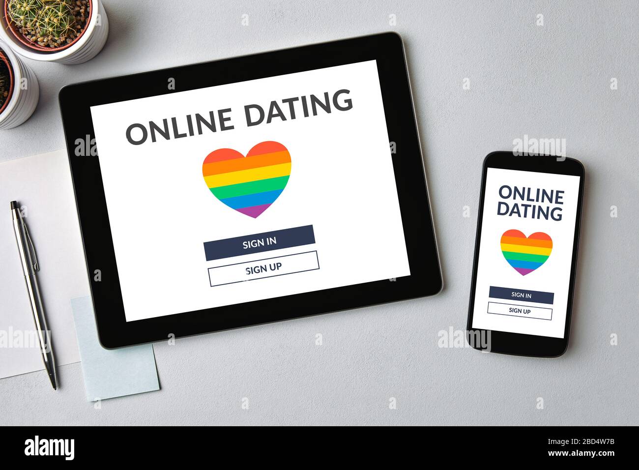 LGBT Dating aplicación concepto en tablet y teléfono móvil pantalla sobre mesa gris. Gay citas en línea. Vista superior Foto de stock