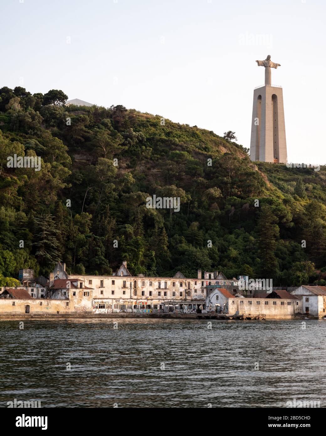 Cristo Rei, Lisboa, Portugal. Santuario de Cristo Rey monumento situado en contra de la arquitectura industrial en ruinas en las orillas del río Tajo. Foto de stock