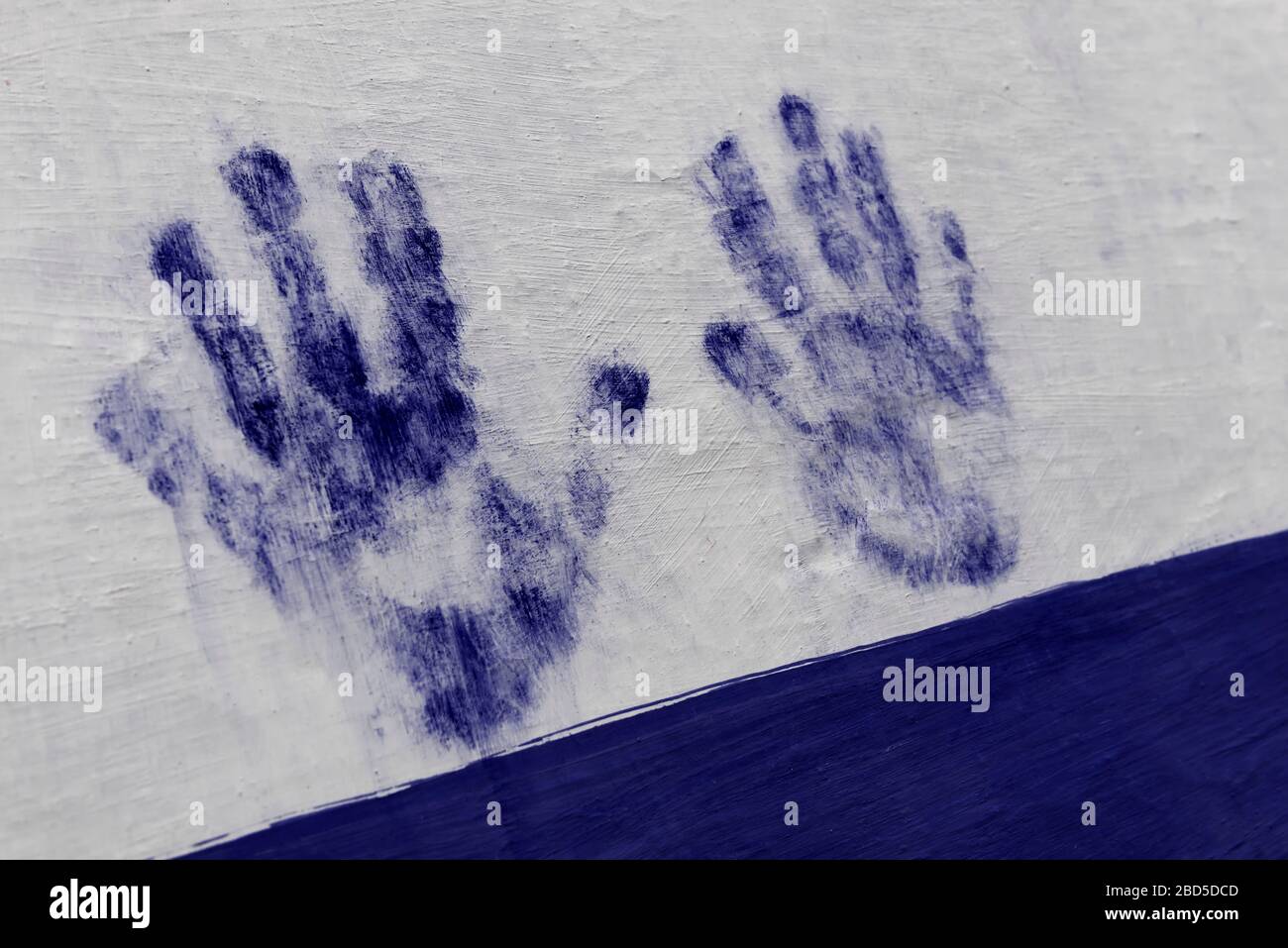 Estampado de manos pintado en azul en una pared blanca. Mano humana, palma, dedos. Imagen conceptual. Foto de stock