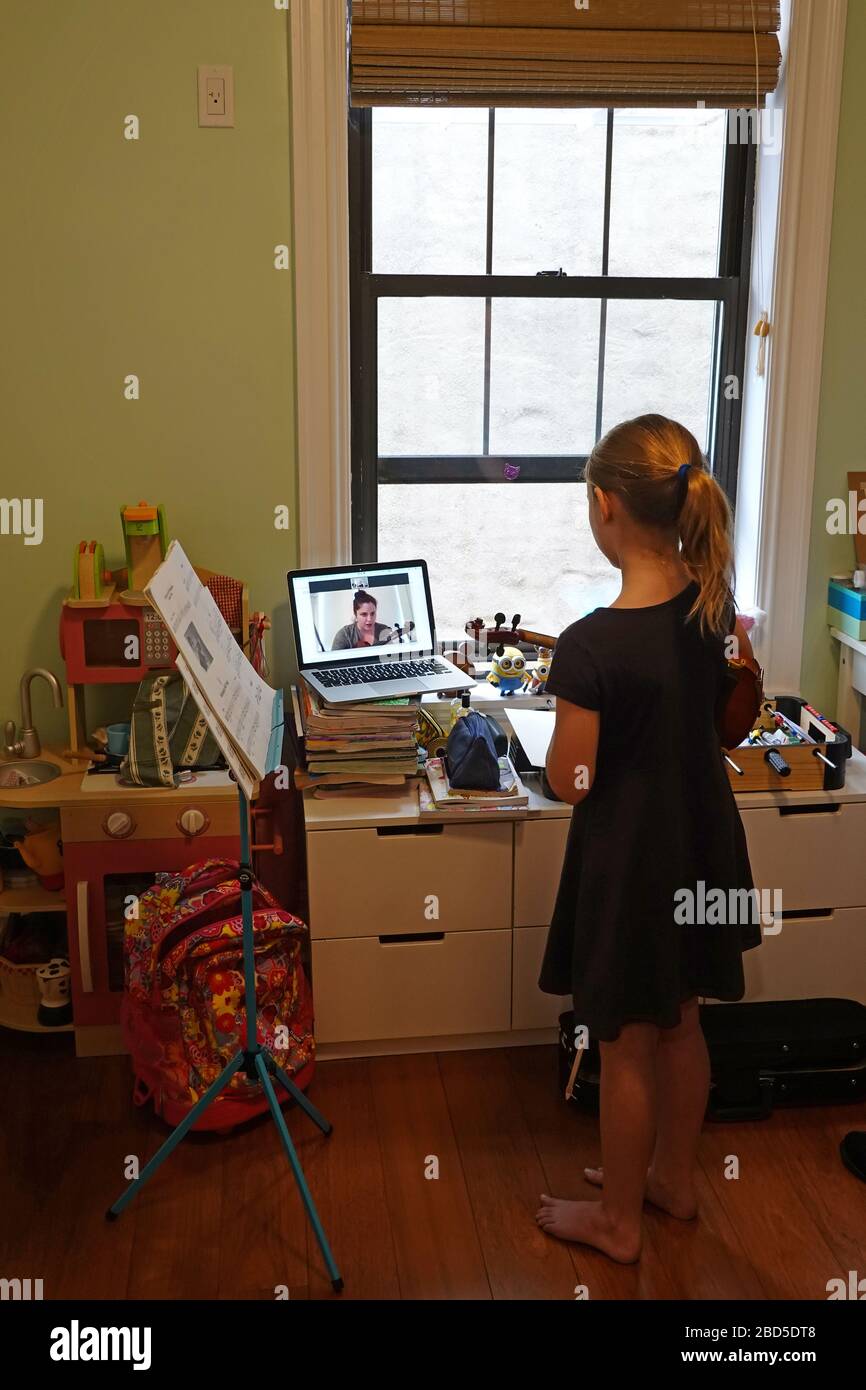 Nueva York, EE.UU. 2020. La colegiala aprendiendo a tocar una viola usando  un ordenador portátil para ver y escuchar a su maestra de música desde su  habitación durante el Coronavirus Fotografía de