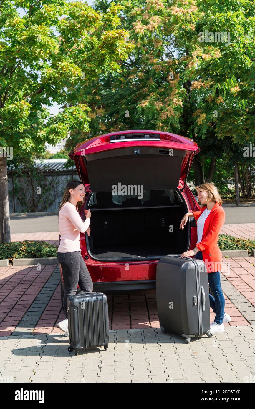 Dos chicas trajeron maletas para abrir el maletero del coche Fotografía de  stock - Alamy