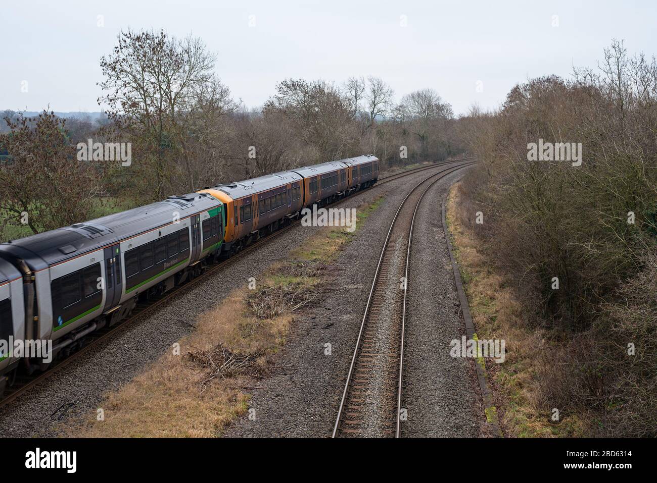 Un tren de cercanías de West Midlands Railway viaja hacia una curva en algunas vías de tren del lado del país. Foto de stock
