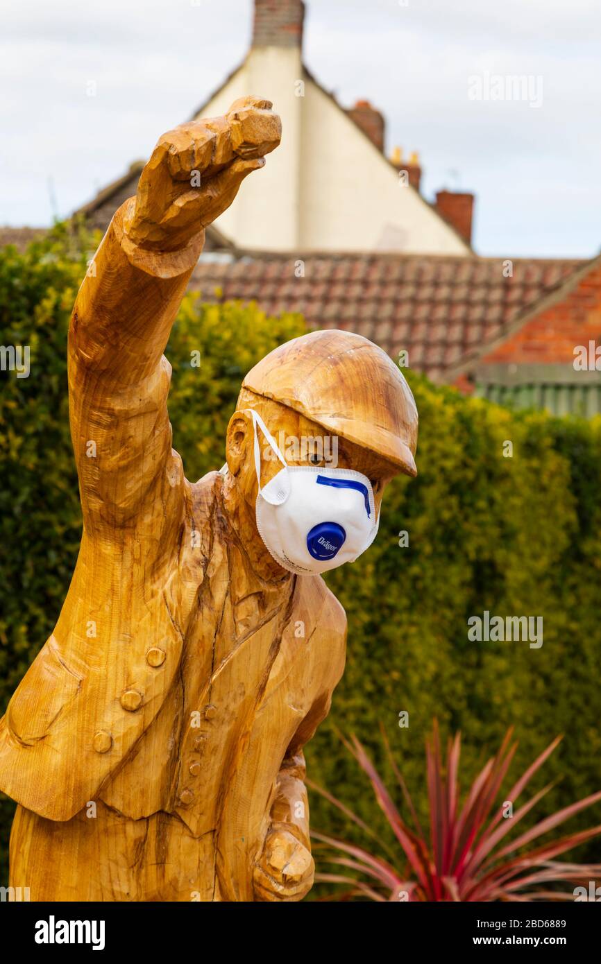 Estatua de “Clockpelter” con máscara médica durante la pandemia del virus de la Corona Covid-19. Great Gonerby, Grantham, Lincolnshire, Inglaterra. Abril 2020 Foto de stock