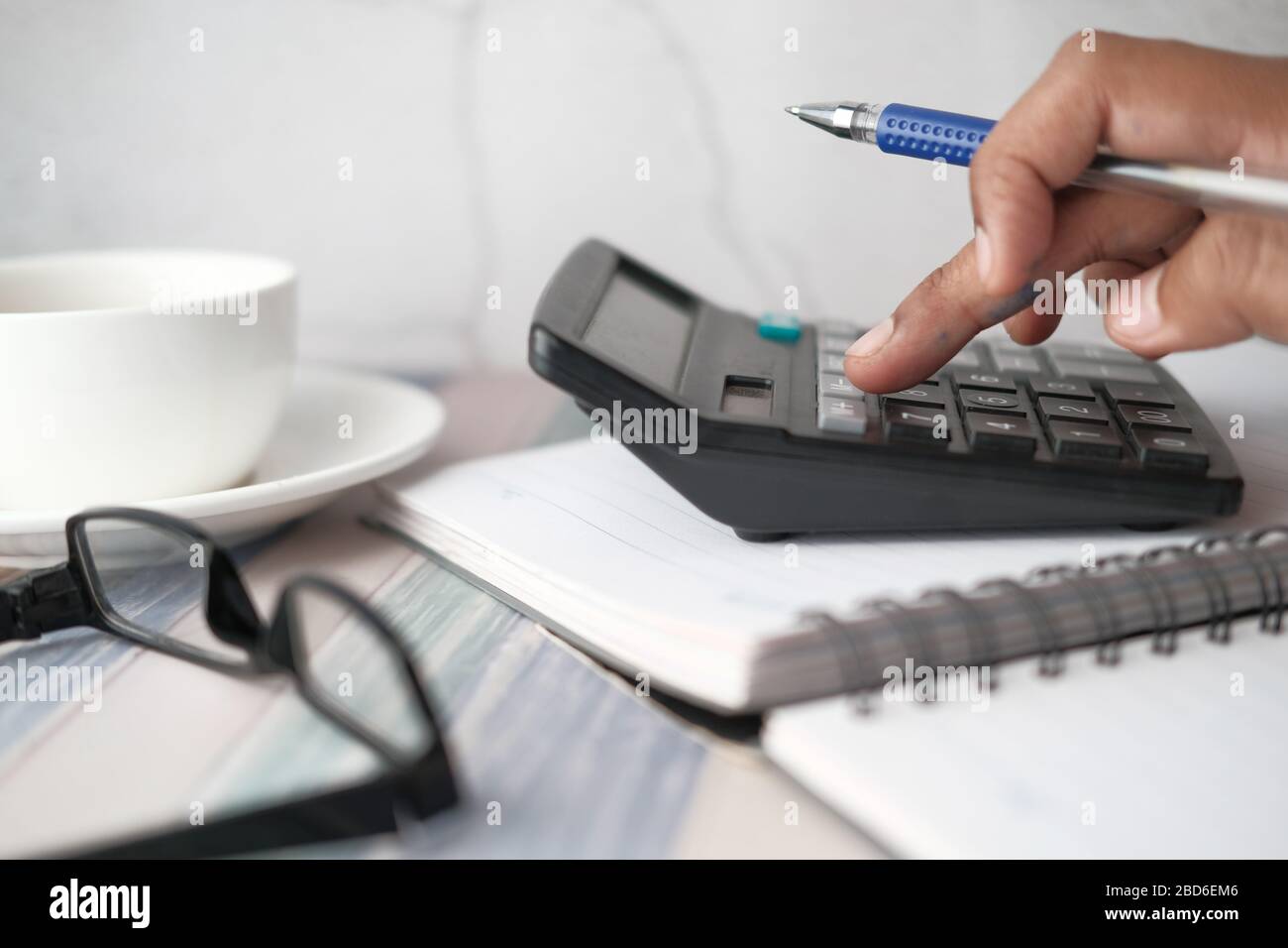 Primer plano de la mano de hombre utilizando la calculadora y el gráfico financiero sobre la mesa Foto de stock