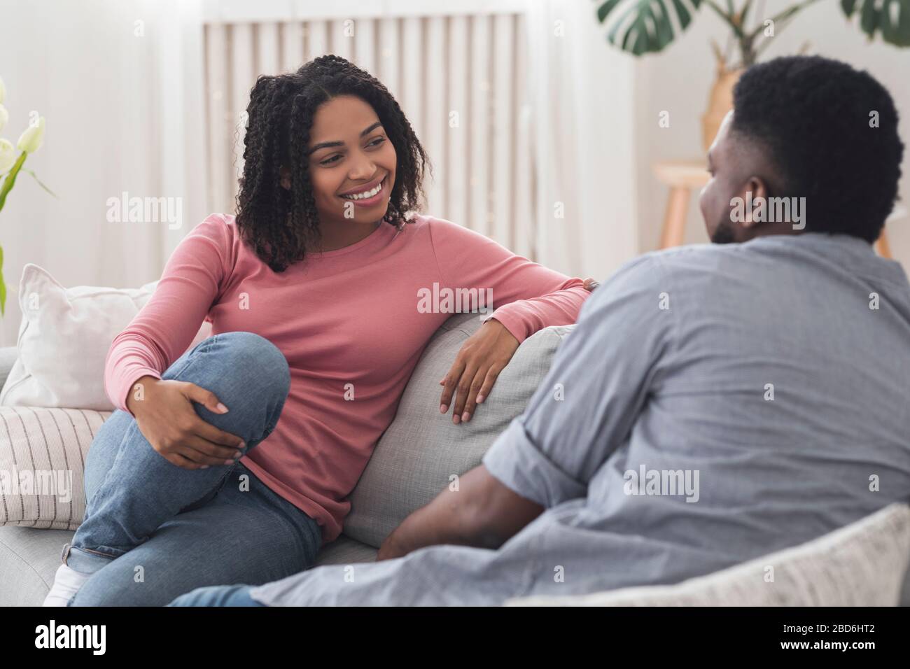 Una pareja de negros casados charlando y descansando en el sofá en casa Foto de stock