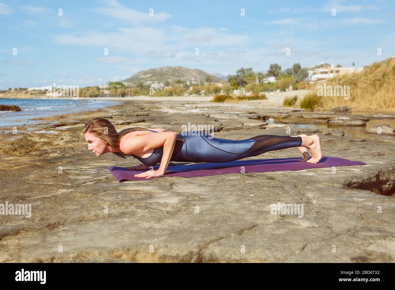 Joven mujer plástica haciendo ejercicios deportivos en la playa Foto de stock