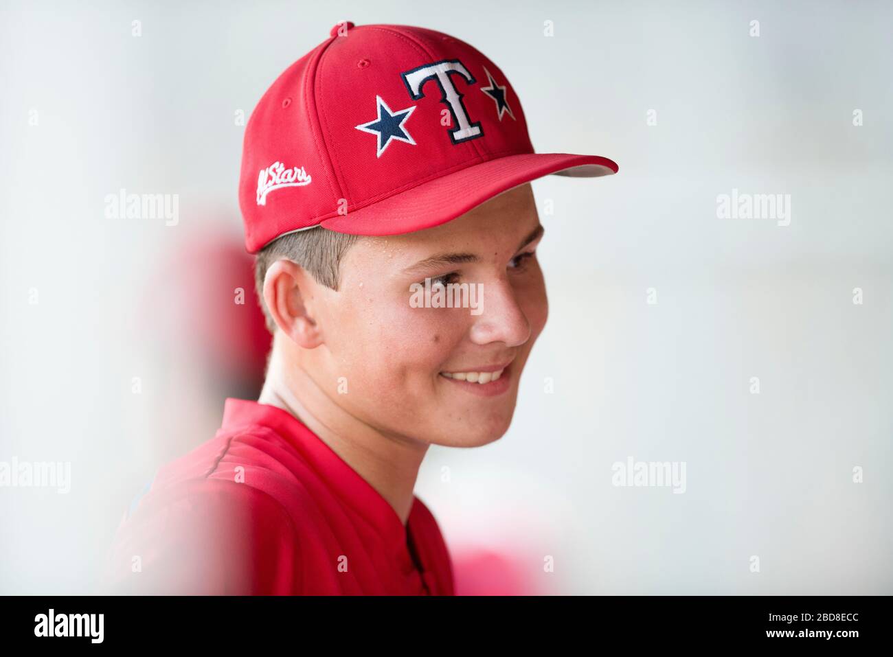 Retrato de primer plano de un jugador adolescente de béisbol con gorro rojo y uniforme Foto de stock