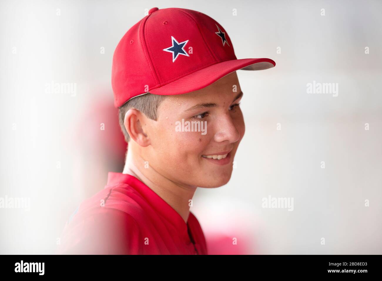 Retrato de primer plano de un jugador adolescente de béisbol con gorro rojo y uniforme Foto de stock