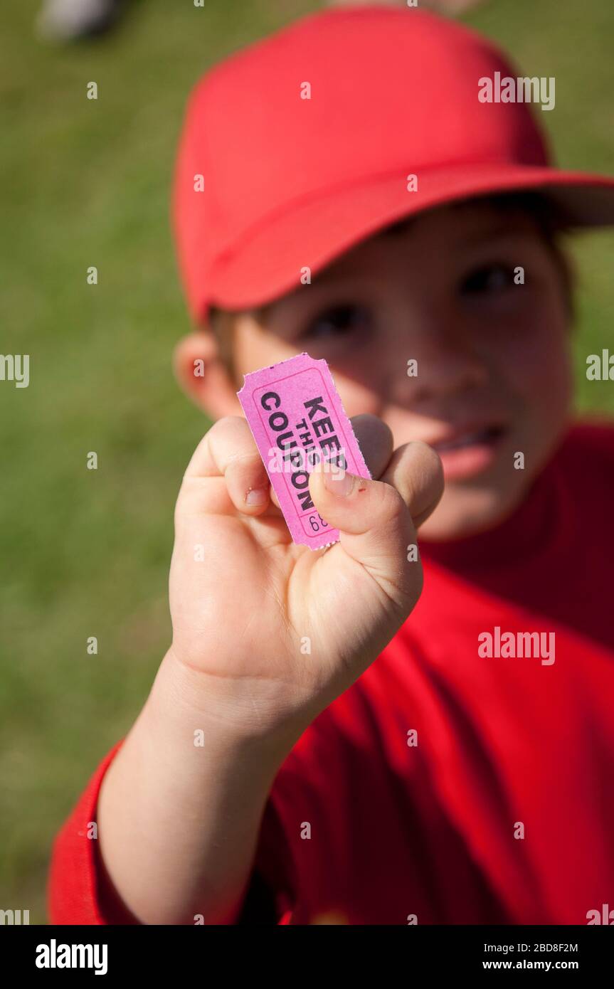Niño pequeño sosteniendo su cupón para la choza de bocadillos después de su pequeño partido de liga Foto de stock