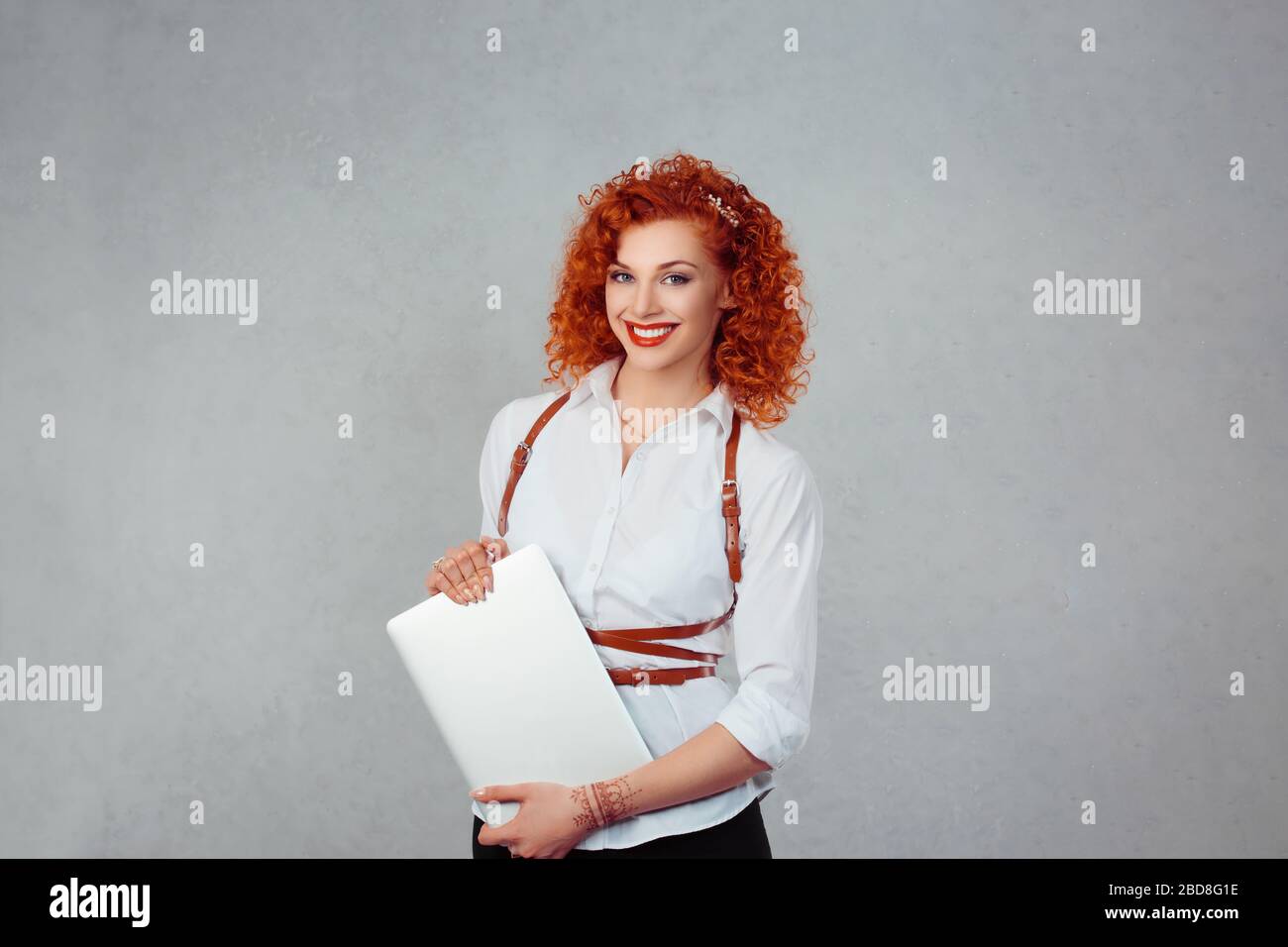 Feliz con el portátil. Retrato de la universidad estudiante Redhead mujer rizado mirar feliz sosteniendo tablet ordenador sonriendo. Multicultural Latina niña rojo labios whit Foto de stock