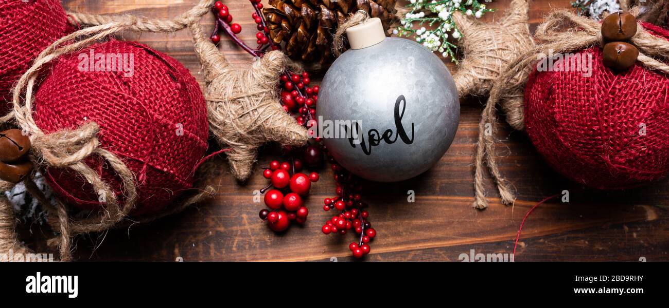 Adornos navideños sobre fondo de madera marrón. Conos de pino, guirnalda, bayas y ramas de pino y bolas Foto de stock