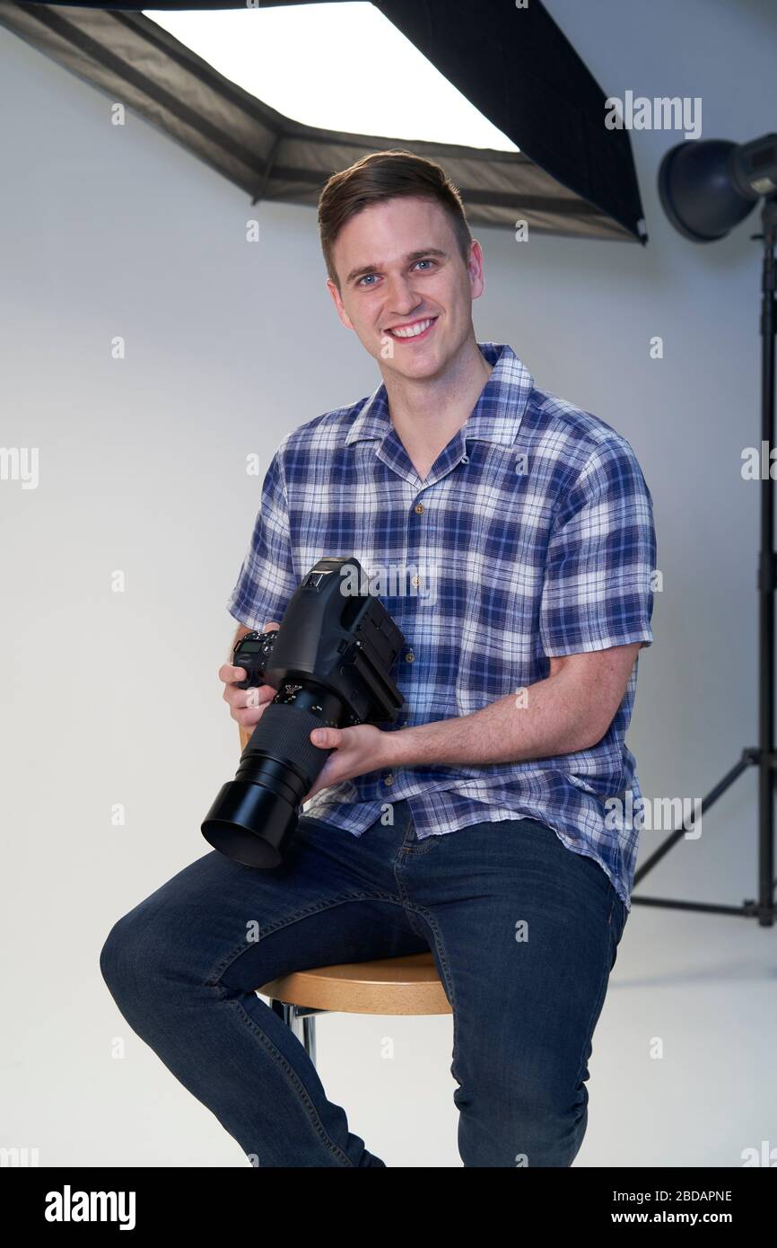 Retrato del fotógrafo macho en Studio para la sesión de fotos con la cámara y aparatos de iluminación Foto de stock