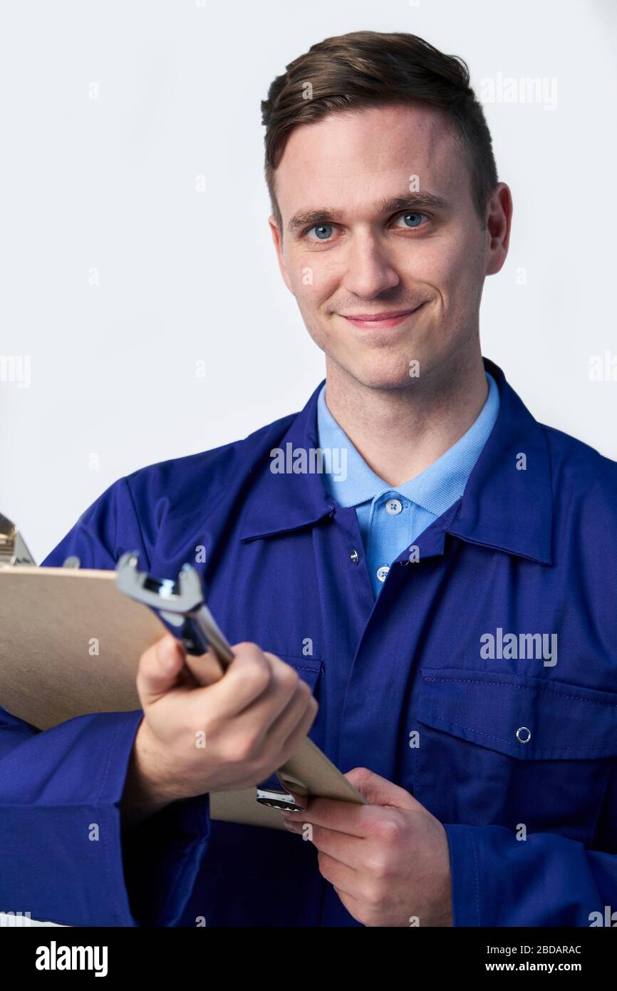 Estudio Retrato de Smiling Ingeniero masculino con portapapeles y Spanner contra fondo blanco Foto de stock