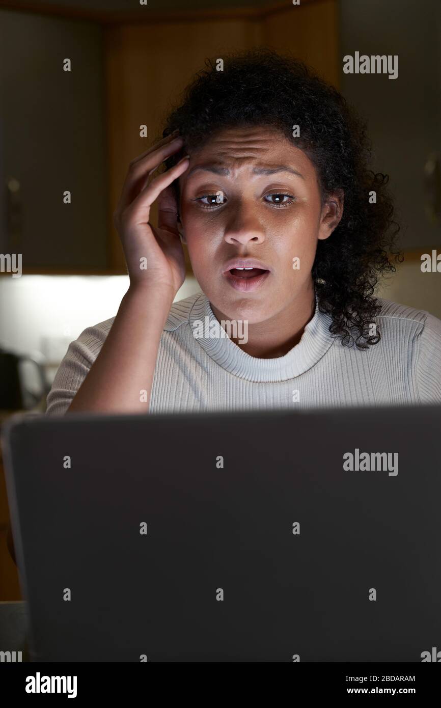 Mujer desgraciada en casa con el ordenador siendo acosado Online en medios sociales Foto de stock