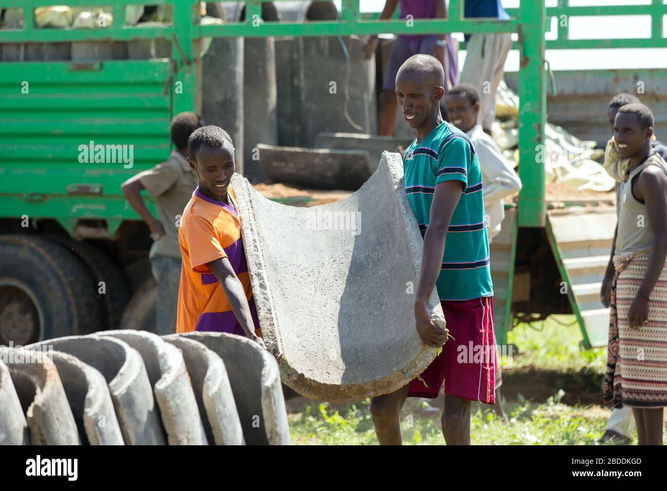 14.11.2019, Gode, Región Somalí, Etiopía - los trabajadores de la construcción descargan tuberías de agua de hormigón para el suministro de agua potable de la aldea Burferedo fr Foto de stock