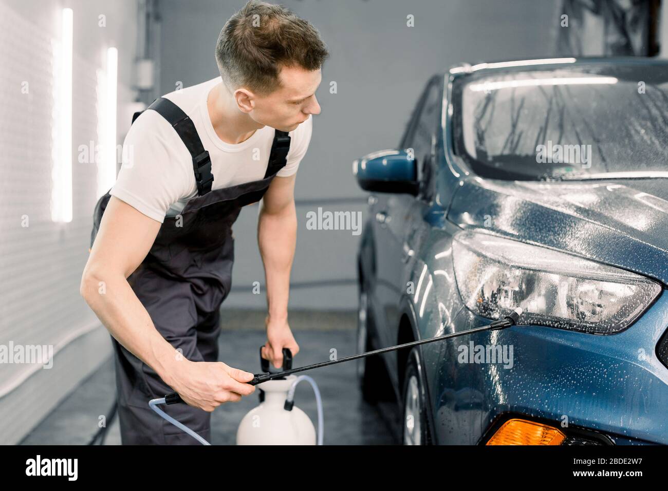 hombre con uniforme y respirador, trabajador del centro de lavado de autos,  limpiando el interior del auto con un limpiador de vapor caliente. concepto  de detalle de coche. 8678096 Foto de stock