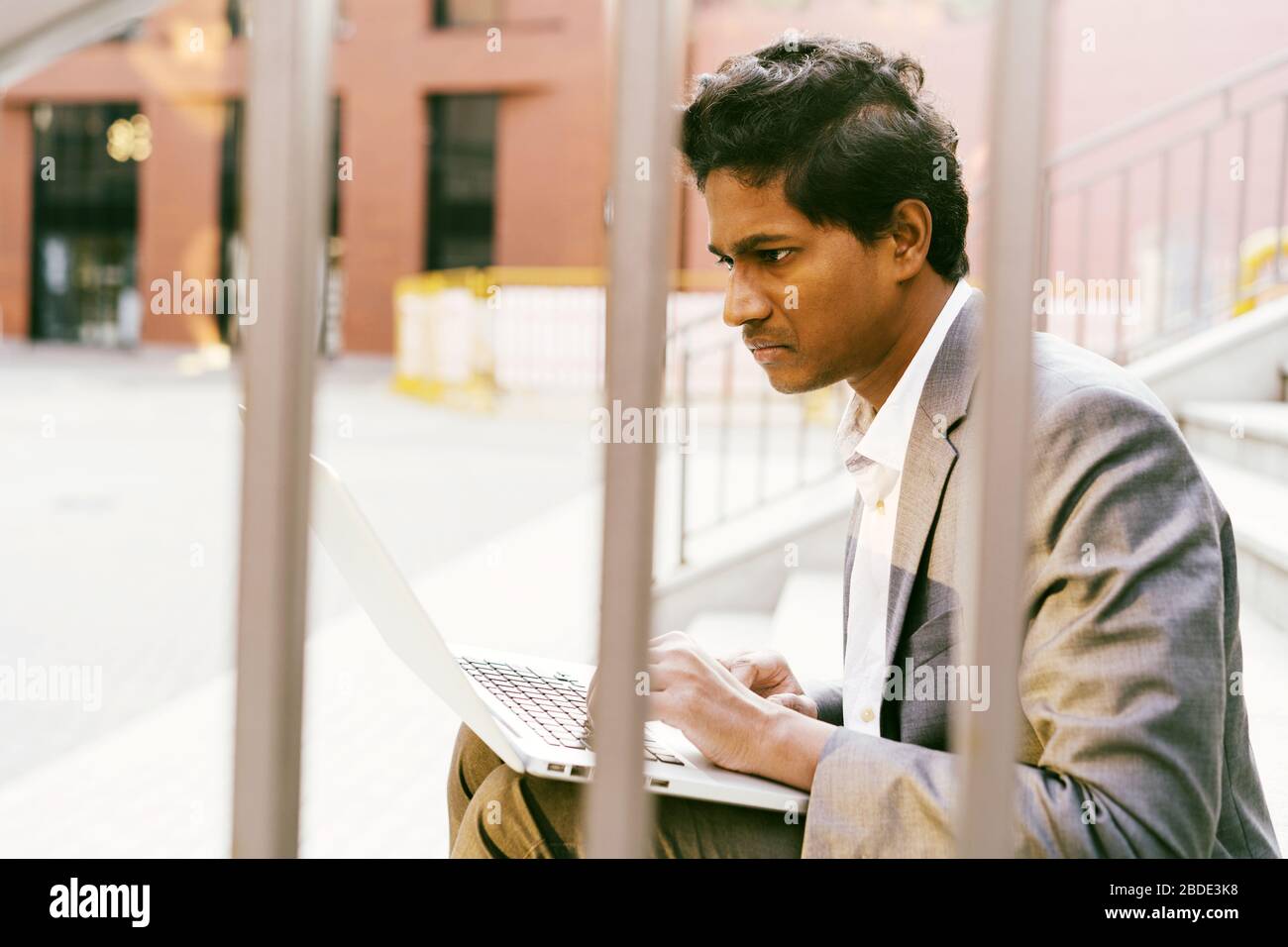 Joven apuesto hombre indio en una camisa blanca y un traje de negocios está sentado Foto de stock