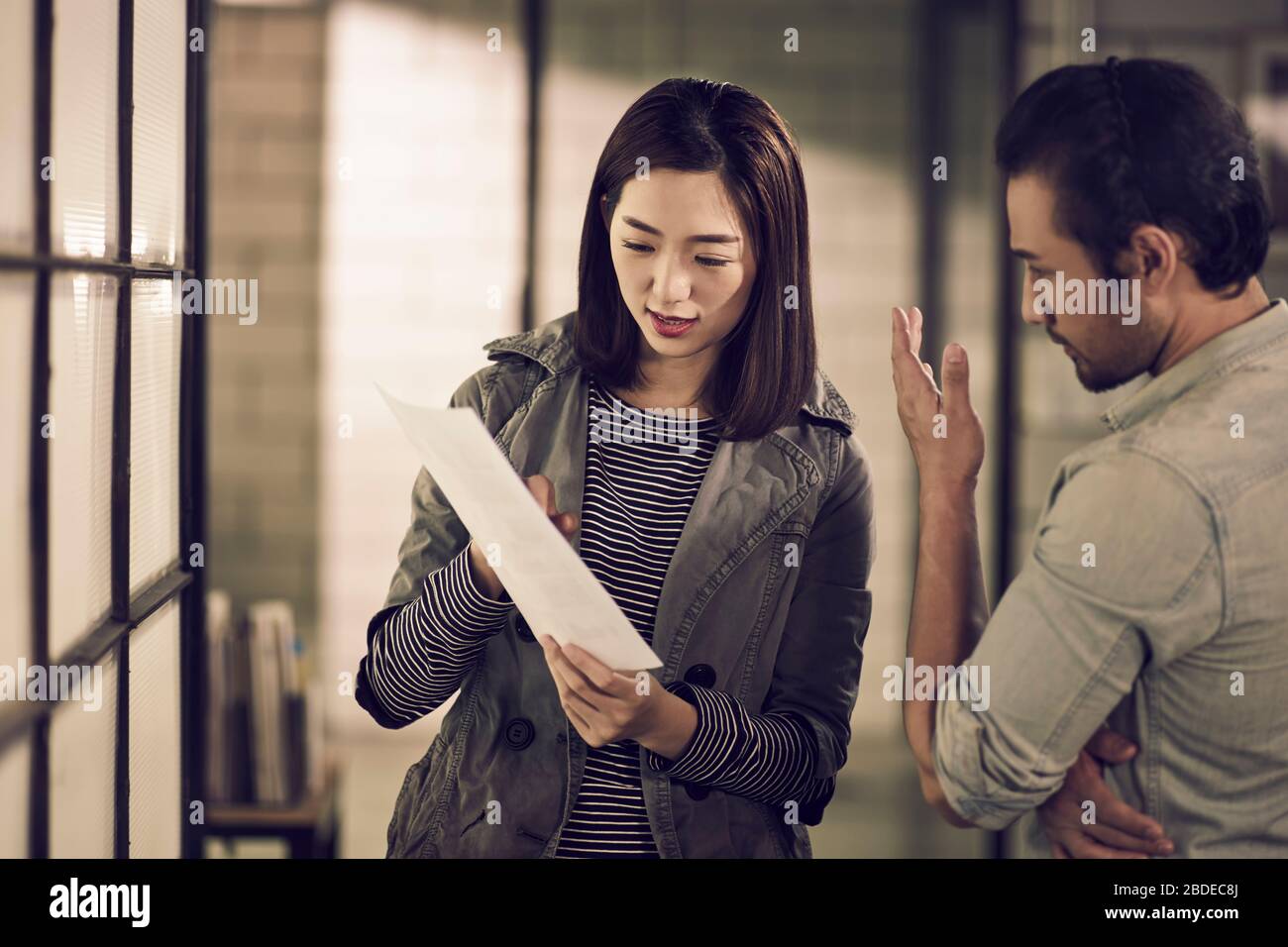 jóvenes empresarios asiáticos hombre de negocios y empresaria mirando un documento que tiene una discusión en el cargo Foto de stock