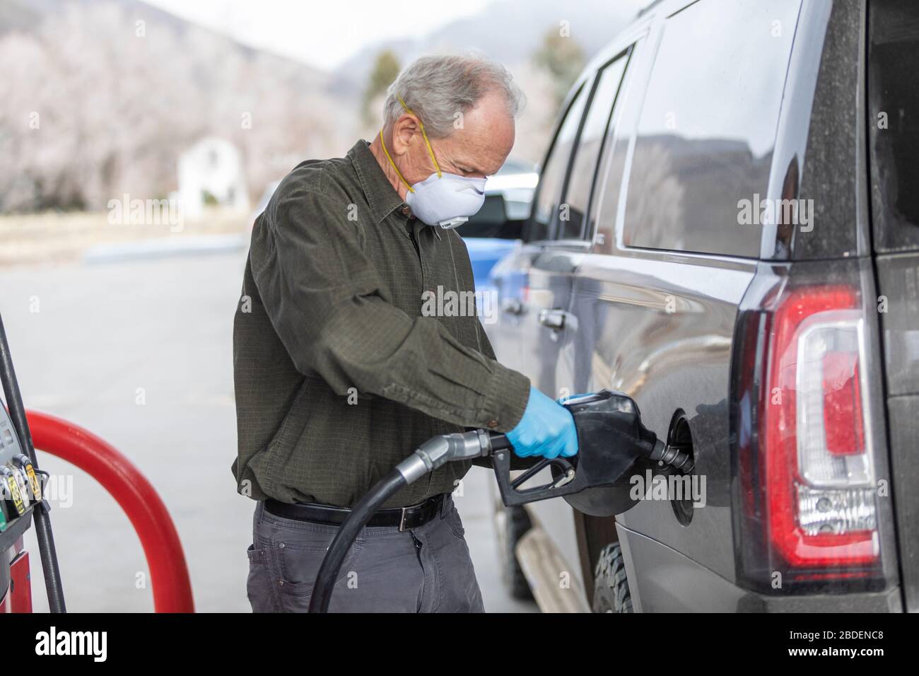 Hombre con guantes quirúrgicos y máscara de repostaje de coches a gas estación Foto de stock