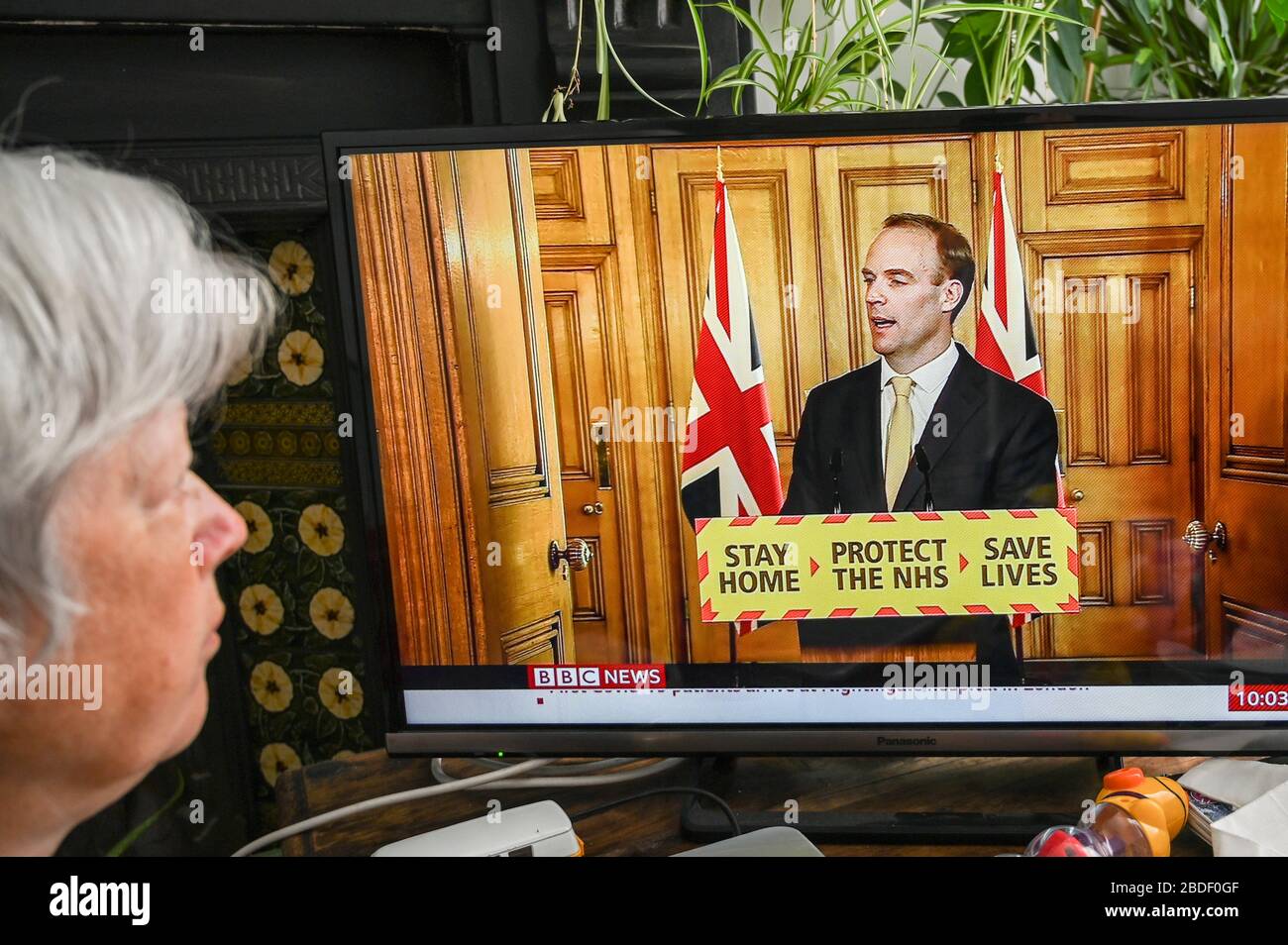 Dominic Raab, primer Secretario de Estado, dando una conferencia de prensa televisada sobre Covid-19; visto por un espectador mayor. Foto de stock