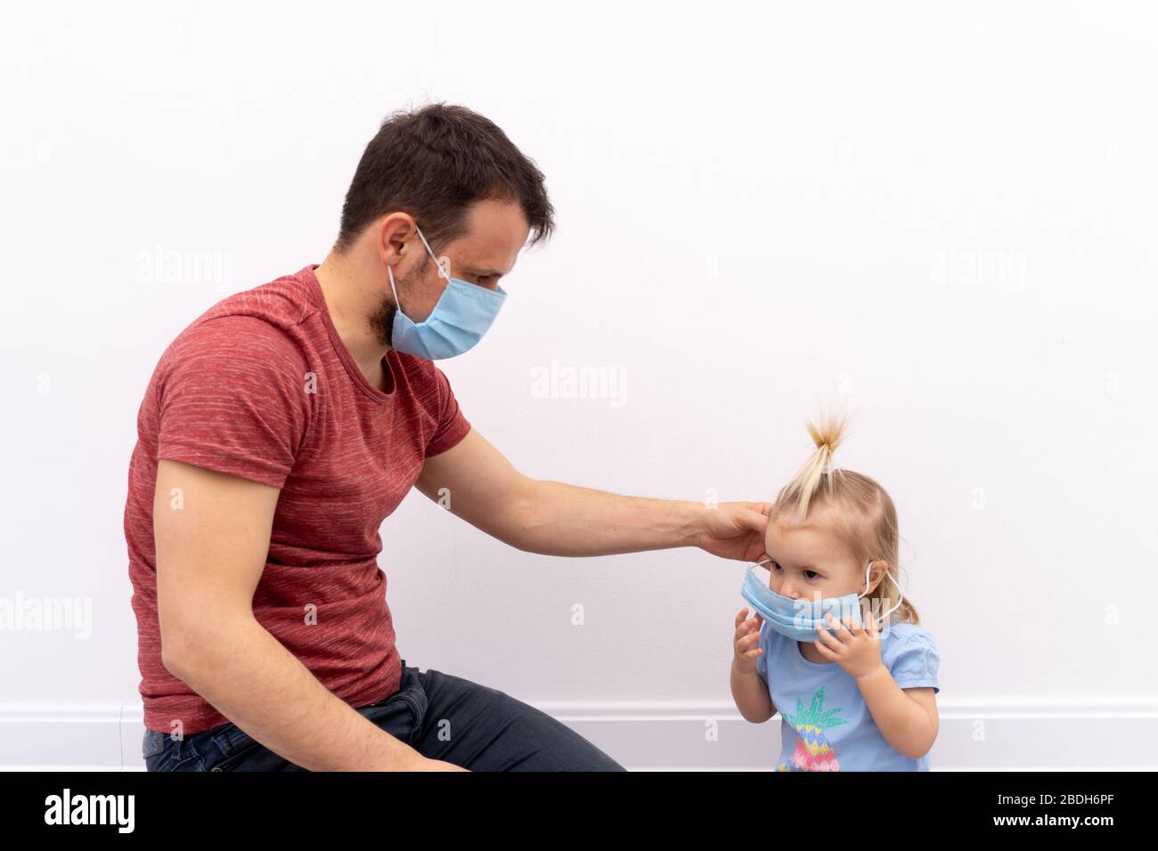 El hombre está poniendo una máscara protectora sobre su hijo Foto de stock